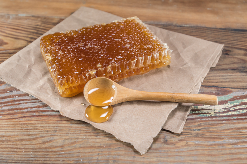 Plástev medu a med na dřevěné lžíci